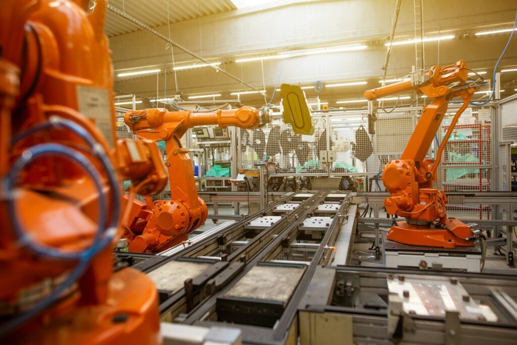 Why Travis Believes New Humanoid Robots Will Power Industrial Revolution a factory filled with lots of orange machines