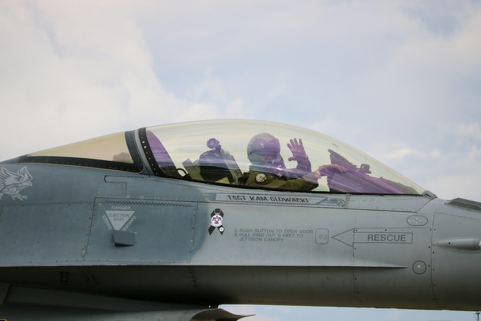 Two pilots in fighter jet cockpit waving