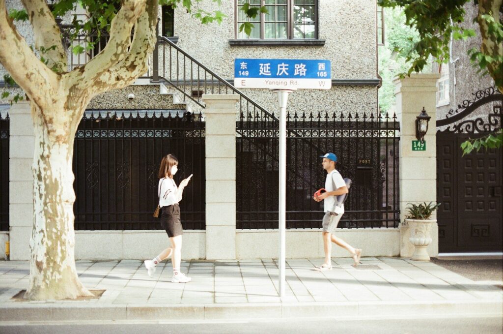 man in white shirt and black shorts standing on sidewalk during daytime