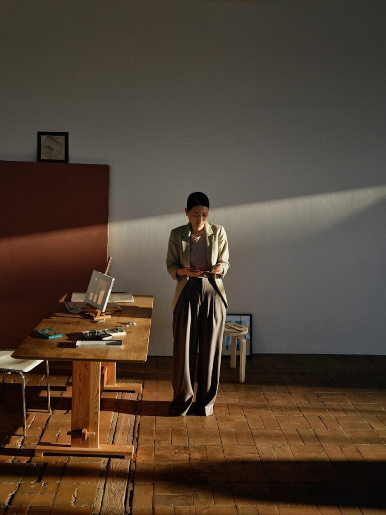 Woman standing in sunlight by a wooden table.