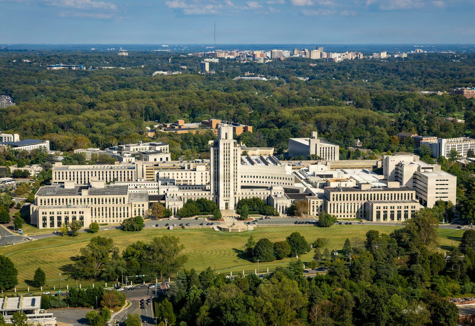 Large institutional buildings surrounded by lush green trees.