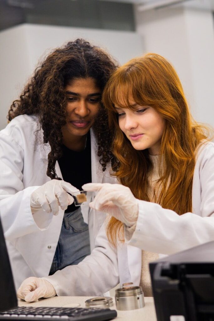 Two women in lab coats examine a sample