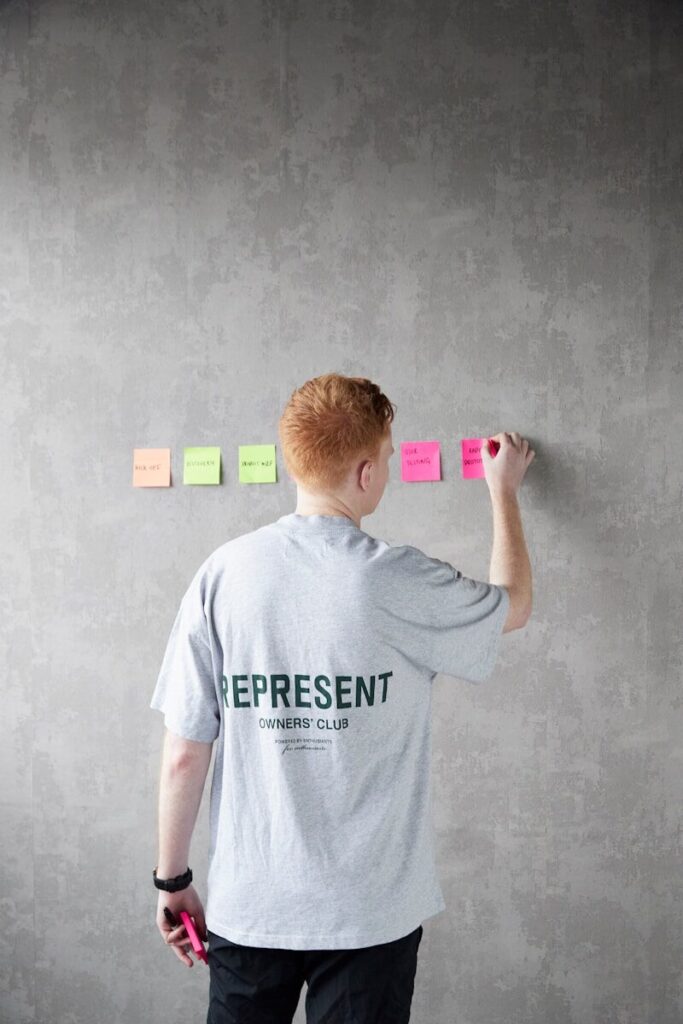 a man standing in front of a wall with sticky notes on it