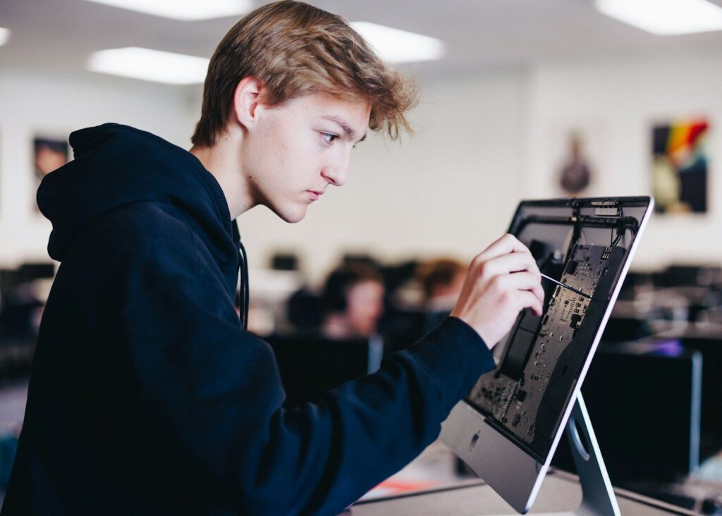 If New AI Can Do Your Homework, Schoolwork Even Necessary? a young man working on a laptop computer