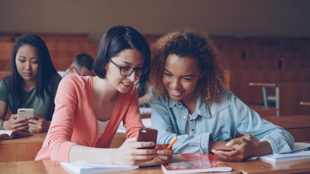 Two students looking at a smartphone in class.