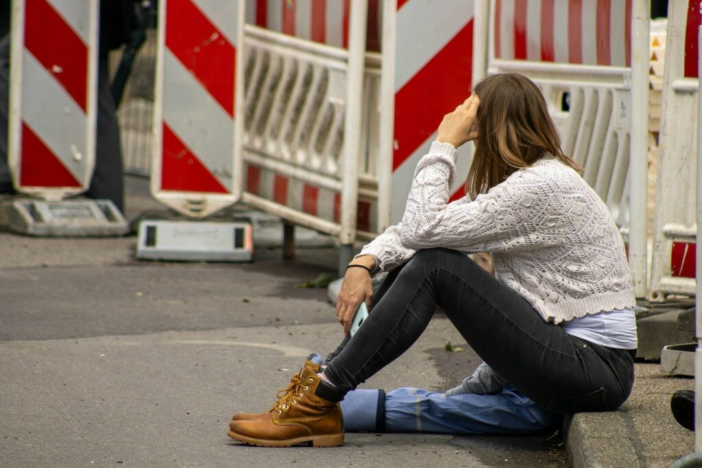 A woman sitting on the ground with her head in her hands