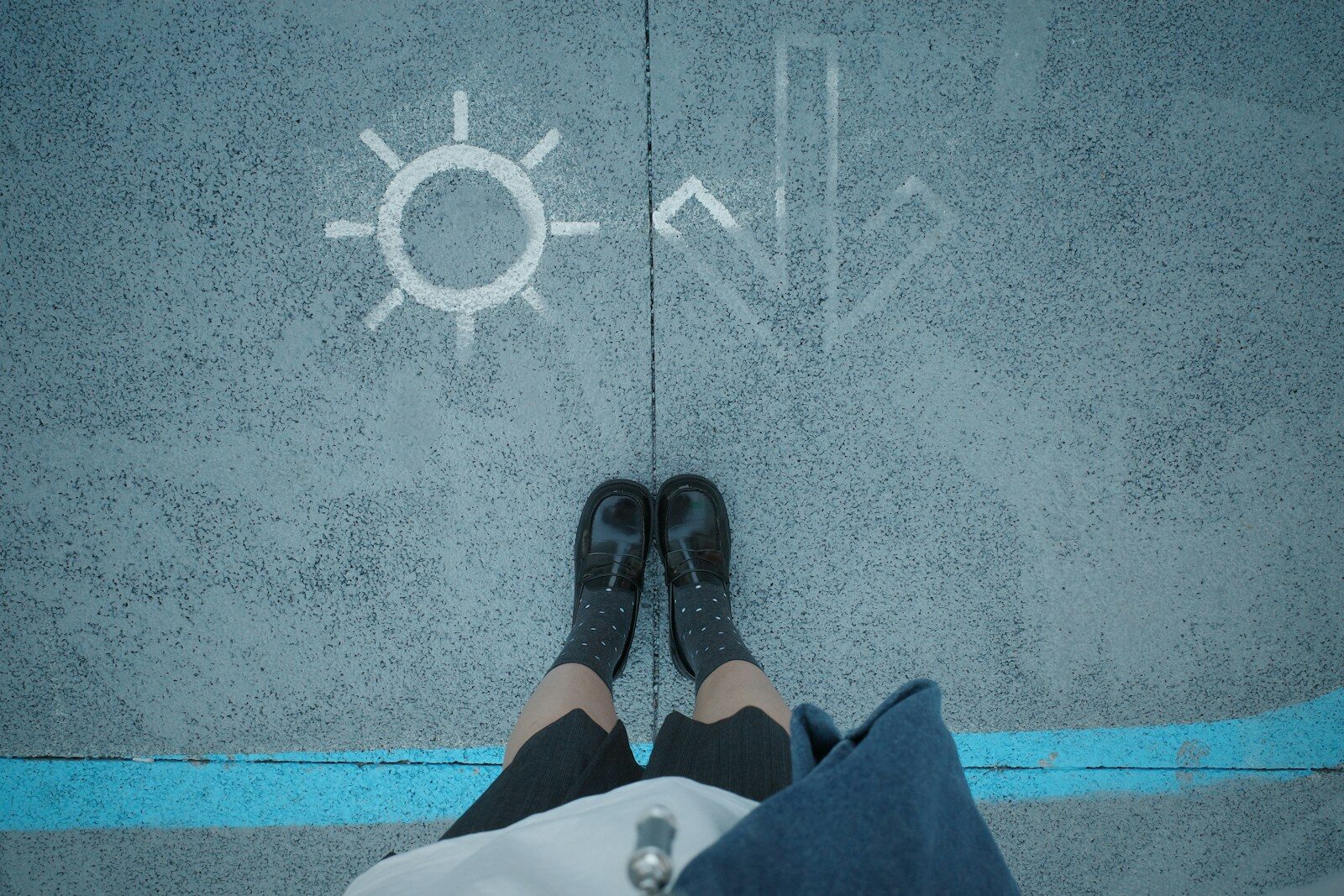 Person standing on pavement with sun and arrow symbols
