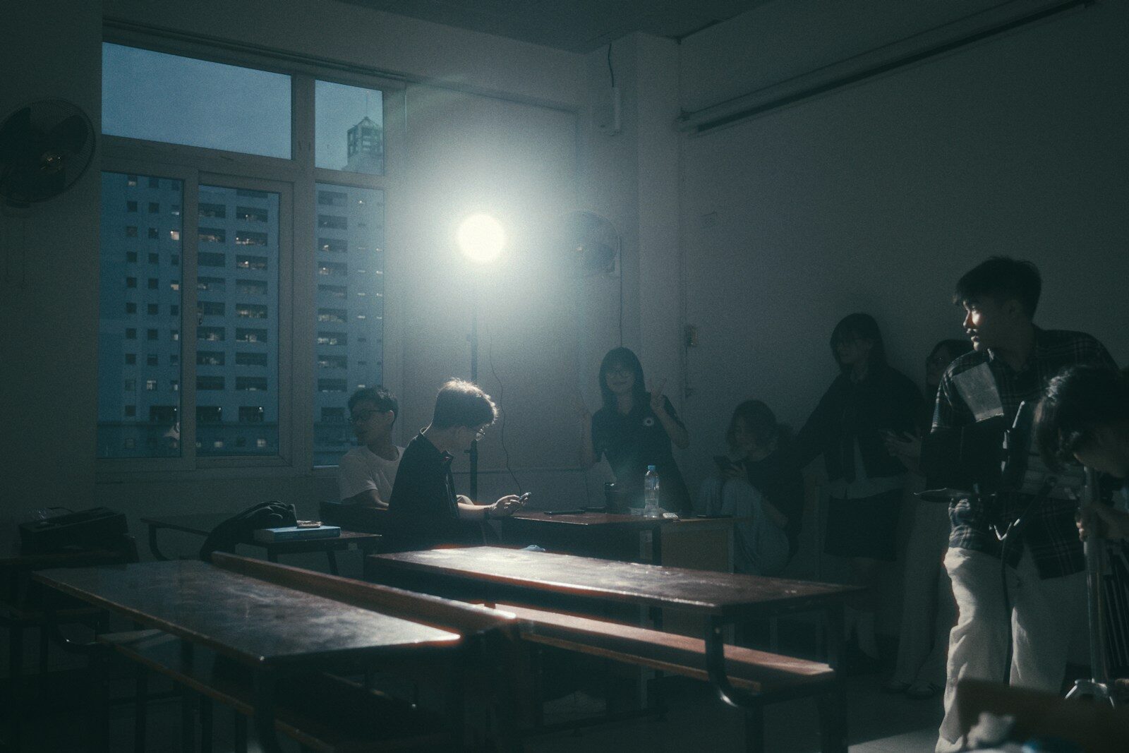 A group of people sit in a dimly lit classroom.