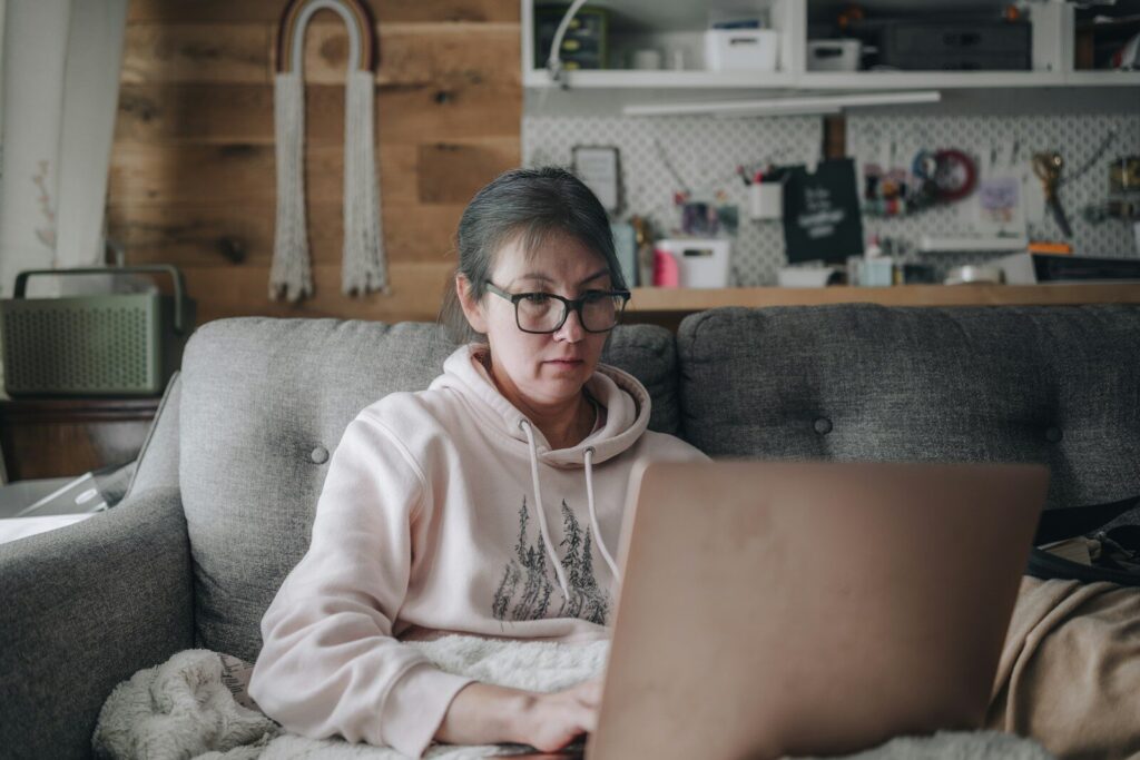 Why Americans Fear New AI More Than Ever And That not Irrational Woman works on laptop while sitting on a couch.