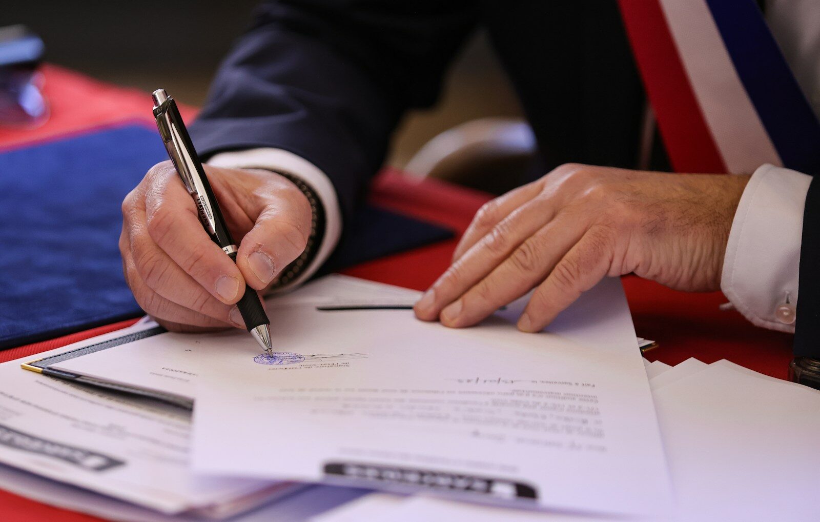 Trump Sudden New AI Policy Reversal Exposes Big Tech Lobbying A person signs a document with a pen.