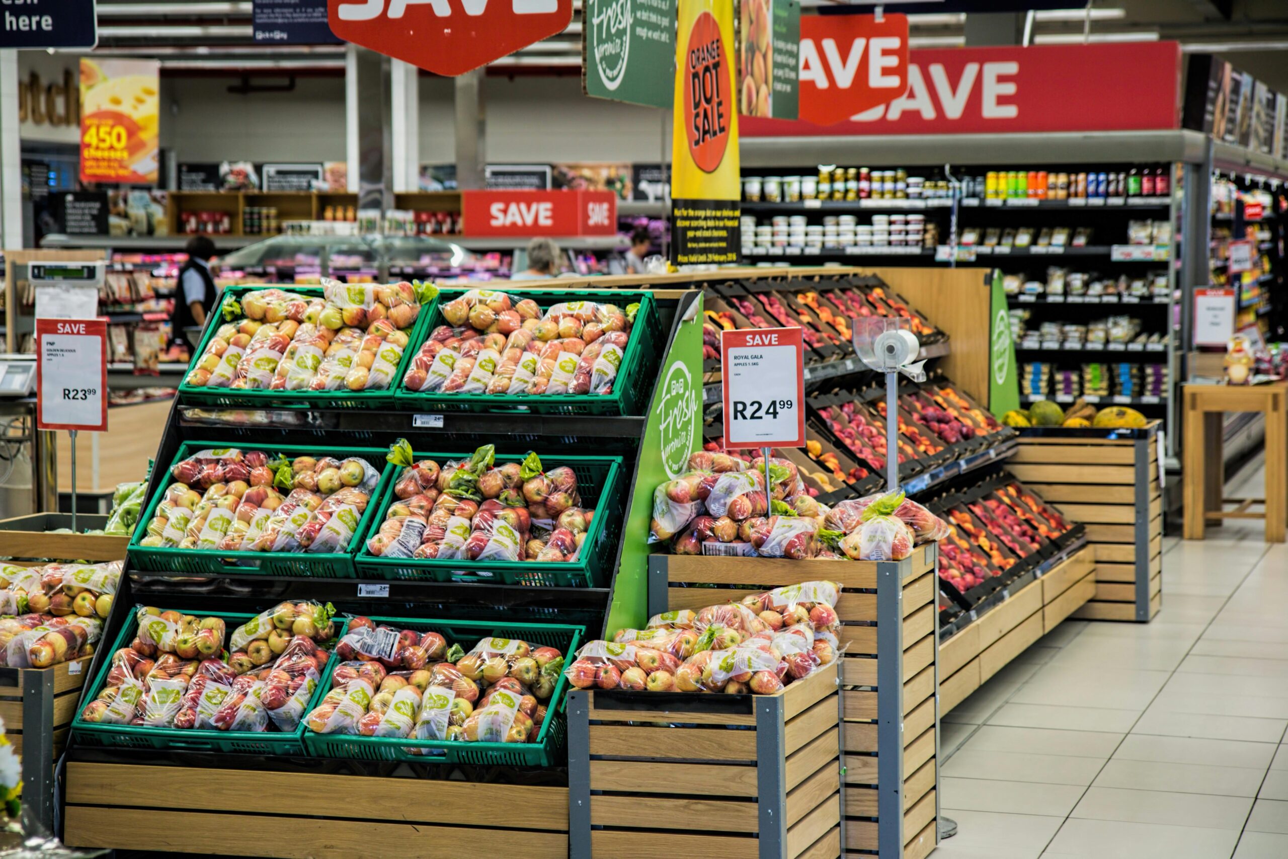 How AI Surveillance Quietly Changing What Pay for New Groceries Colorful produce aisle in a supermarket showcasing fresh apples with discount signage.