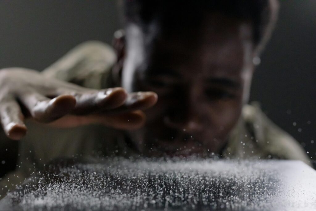 A close-up shot of a man focusing on water drops with his hand extended.