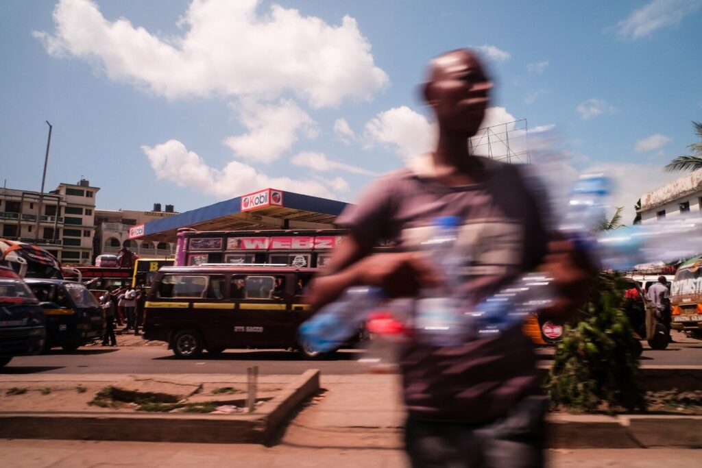 How Kenya’s Digital Health Revolution Is Pricing Out the Poor man holds empty water bottles while crossing the street