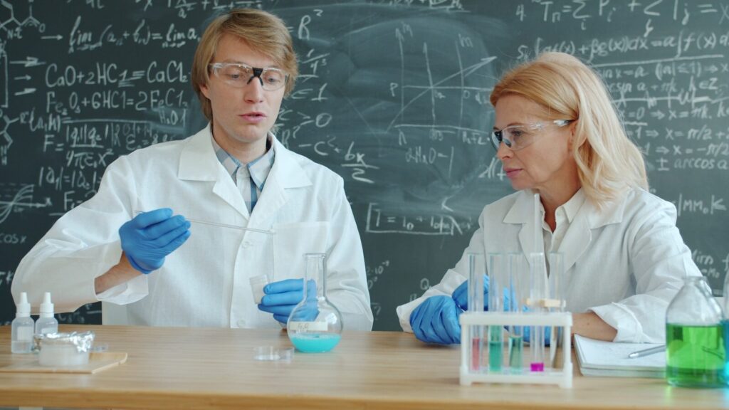 Two scientists in lab coats working with chemicals.