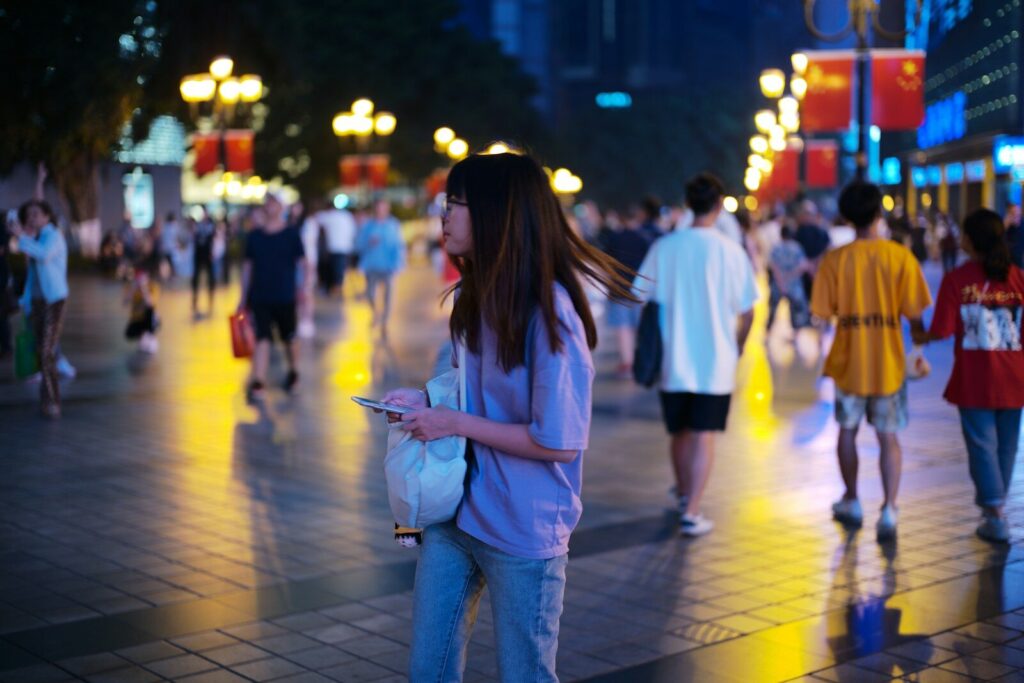 China’s New AI Super-Apps Are Rewiring the Internet Young woman walking on a busy city street at night.