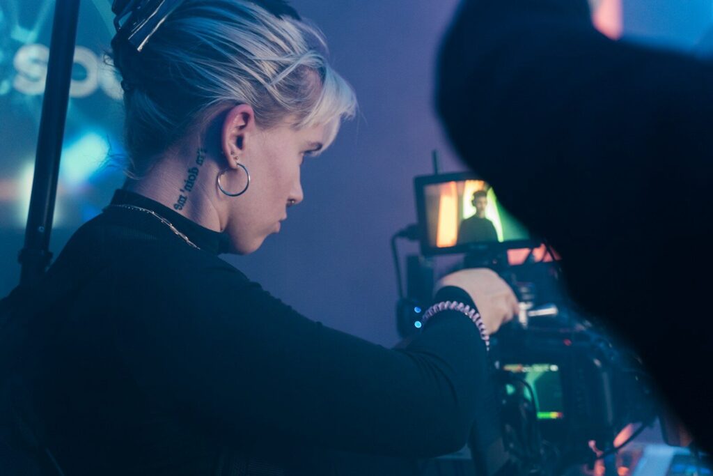 Why AI Startups Spending Huge Money on New Hype Videos a woman in a black top is looking at a video camera