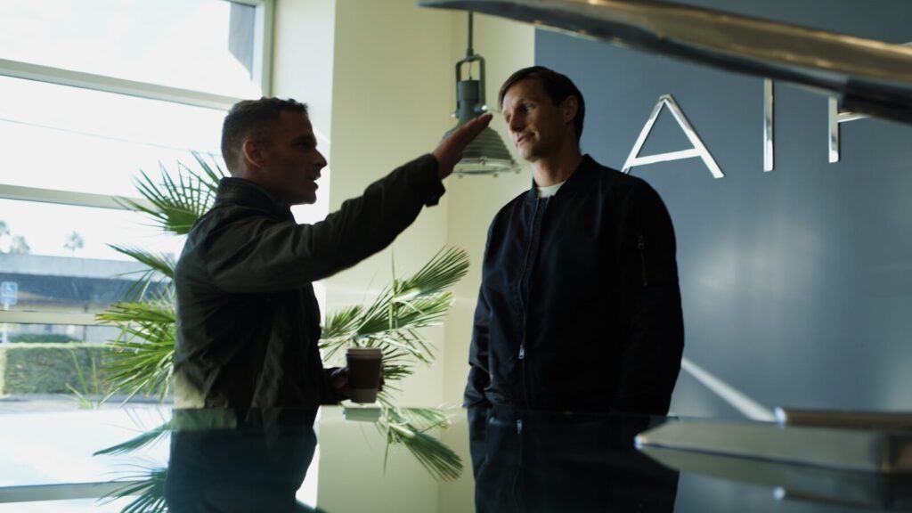 Companies Are Still Waiting for the New AI Productivity Boom Two men talking near an airplane model.
