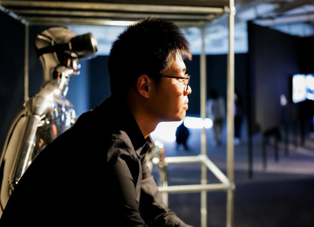 China's Humanoid Robot Revolution Has a New Surprising Problem a man sitting in front of a bike in a room