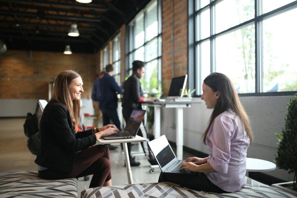 Inside Rise of New “Tokenmaxxing” and Why Companies Use More AI two women sitting on a bed using laptops