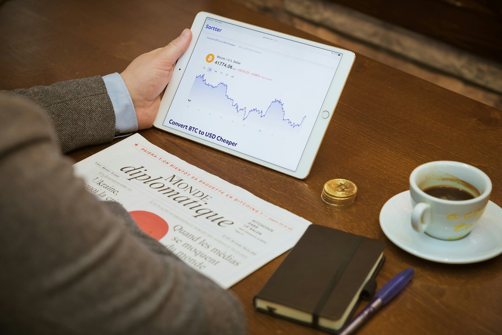 a person sitting at a table with a tablet and a cup of coffee