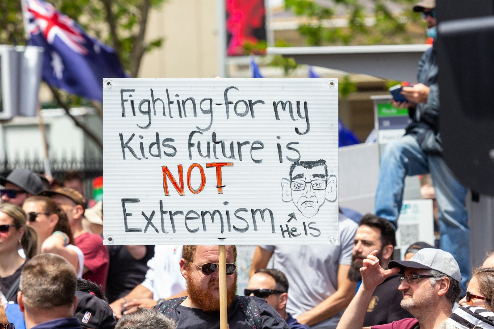 a man holding a sign that says fighting for my kids future is not extre