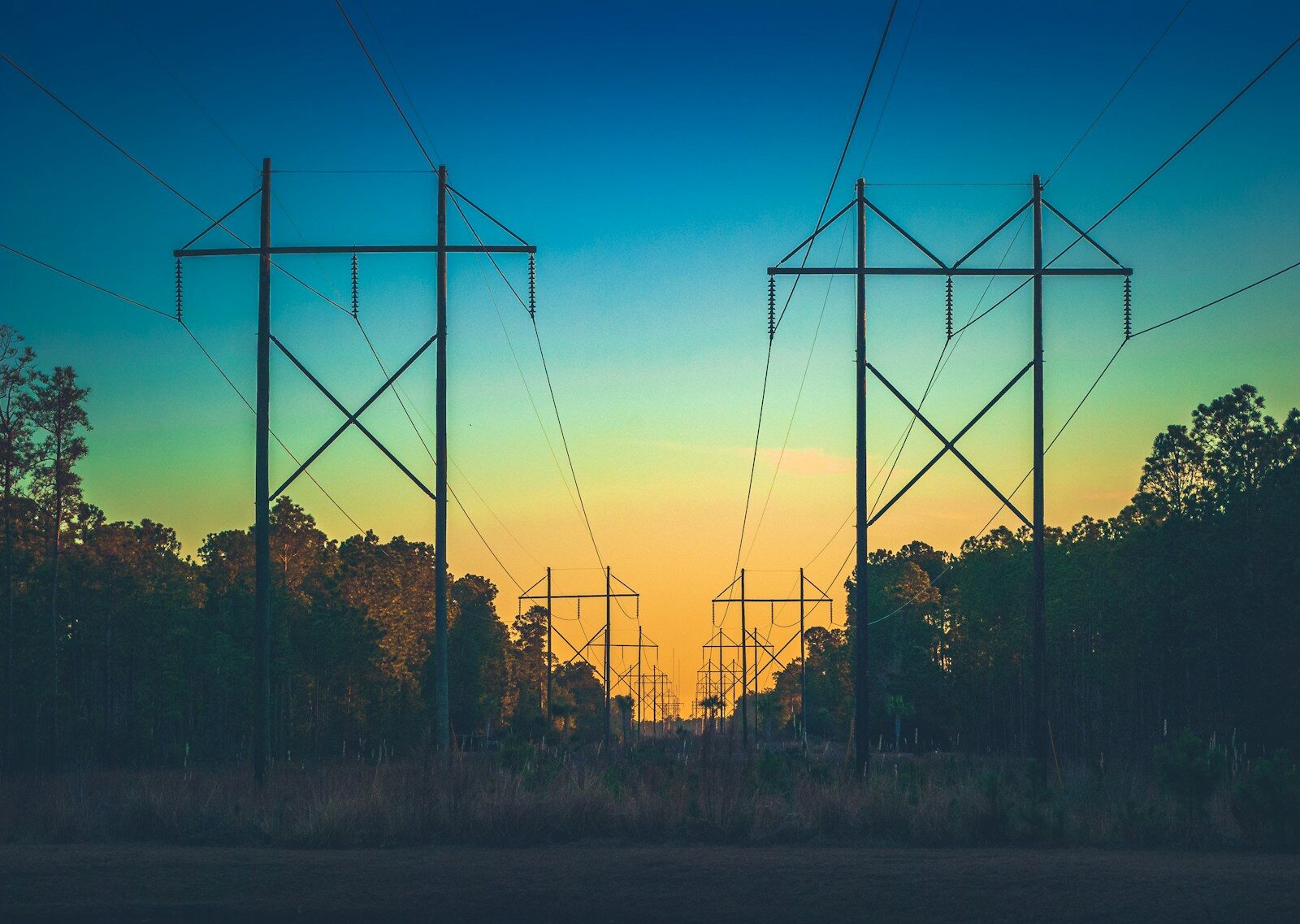 the sun is setting behind some power lines