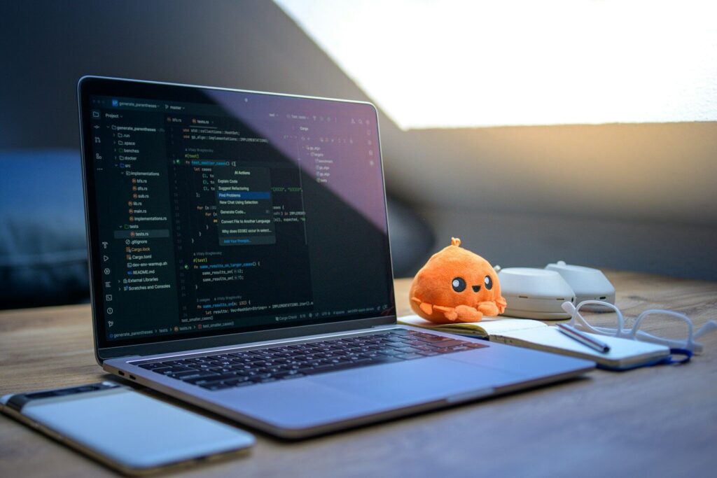 When Artificial Intelligence Creates More New Problems Than It Solves Laptop with code, phone, glasses, and plush toy.