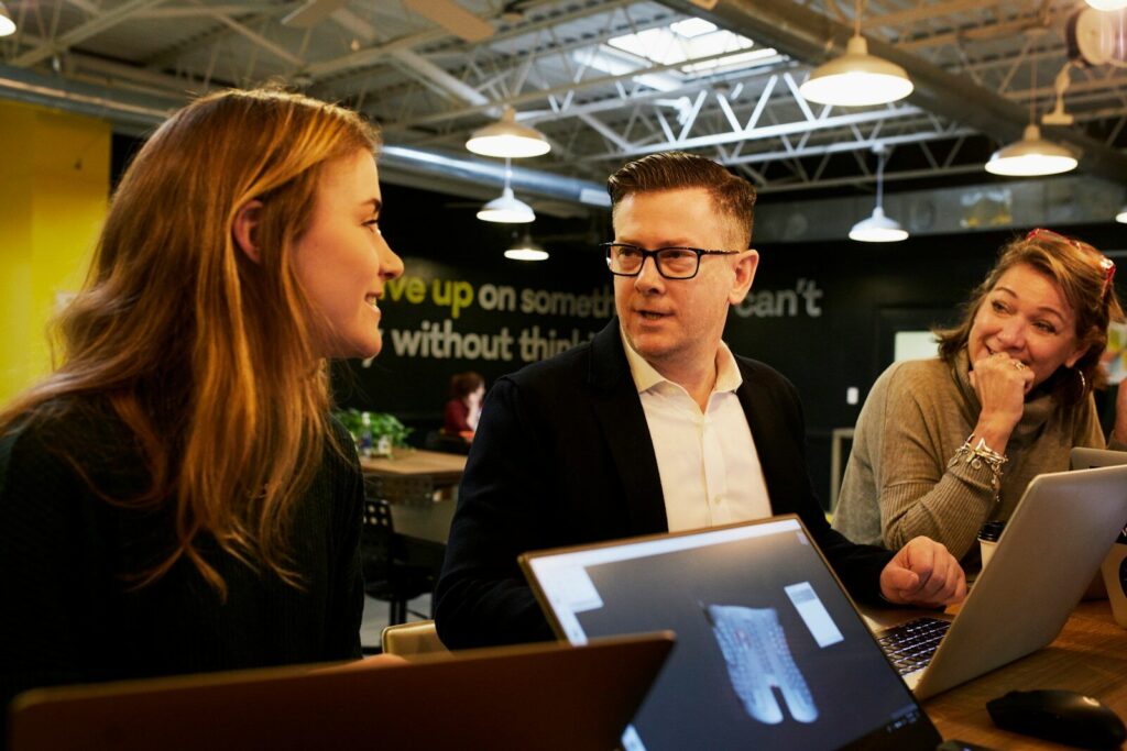 How AI Reshaping New Workforce Instead of Simply Replacing It man and two women sitting beside table