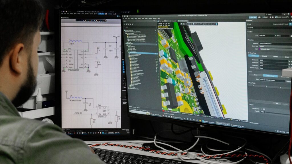 Man looking at circuit board design on computer screen.