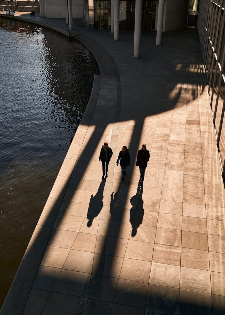 The White House’s Growing Role in New Frontier AI a group of people walking down a sidewalk next to a body of water