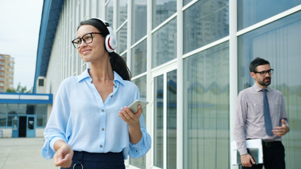 Why Technology Executives Are Facing Rising New Security Concerns Woman with headphones walks past a man outside building