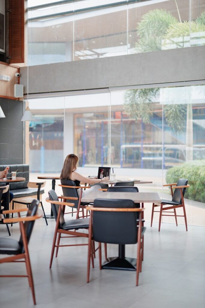 Why New Elite Students Are Choosing Entrepreneurship Over Traditional Internships Woman working on laptop in a bright, modern cafe.